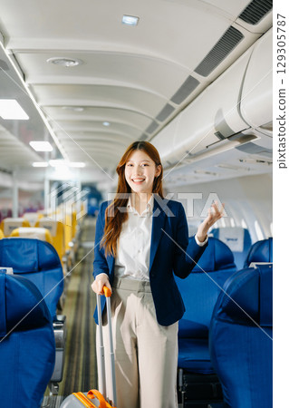 Asian female passenger of airplane sitting in comfortable seat while working laptop and tablet. Travel in style, Asian female passenger of airplane sitting in comfortable seat while working laptop and tablet. Travel in style, 129305787
