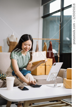 Startup small business SME, Entrepreneur owner woman using smartphone or tablet taking receive and checking online purchase shopping order Startup small business SME, Entrepreneur owner woman using smartphone or tablet taking receive and checking online purchase shopping order 129305818