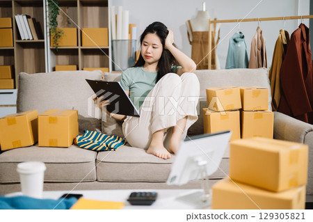 Asian owner woman prepare parcel box woman is stressed, bored, and overthinking from working and standing check online orders for deliver to customer. Asian owner woman prepare parcel box woman is stressed, bored, and overthinking from working and standing check online orders for deliver to customer. 129305821