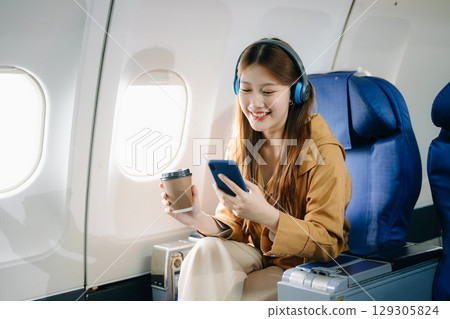 Smiling woman in first-class airplane seat, showcasing luxury, comfort, and elegance in travel. 129305824