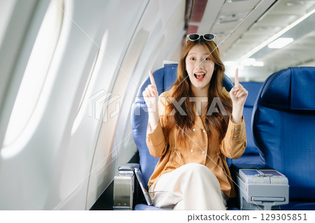 Smiling woman in first-class airplane seat, showcasing luxury, comfort, and elegance in travel. Smiling woman in first-class airplane seat, showcasing luxury, comfort, and elegance in travel. 129305851