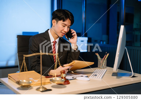 Business professional in suit discussing legal documents over phone, showcasing a formal office setting with a focus Business professional in suit discussing legal documents over phone, showcasing a formal office setting with a focus 129305880