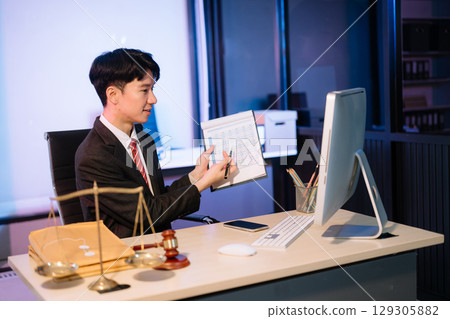 Business professional in suit discussing legal documents over phone, showcasing a formal office setting with a focus Business professional in suit discussing legal documents over phone, showcasing a formal office setting with a focus 129305882