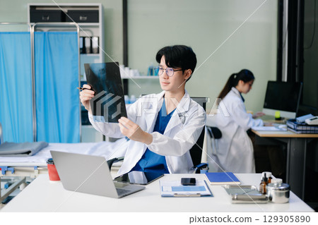Doctor analyzing patient data on tablet in clinical lab. Medical professional in hospital with laptop, blood samples 129305890