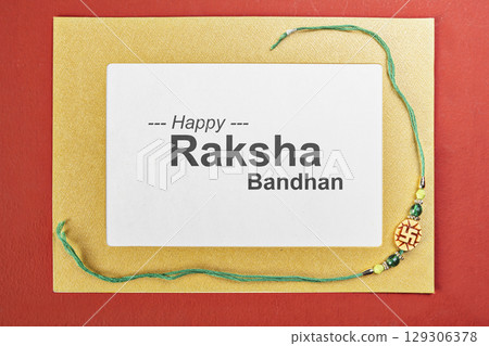 Closeup view of colorful rakhis with a message of Happy Raksha Bandhan on the paper with a colored background. Celebrating the bond of love and protection. Concept of the Raksha Bandhan festival 129306378