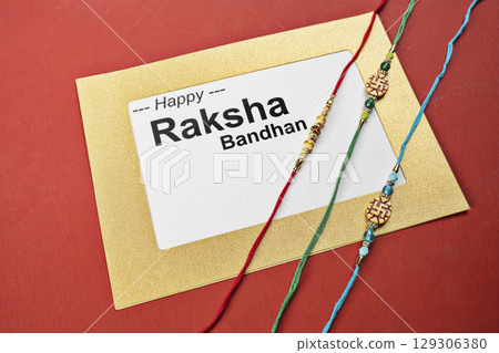 Closeup view of colorful rakhis with a message of Happy Raksha Bandhan on the paper with a colored background. Celebrating the bond of love and protection. Concept of the Raksha Bandhan festival 129306380