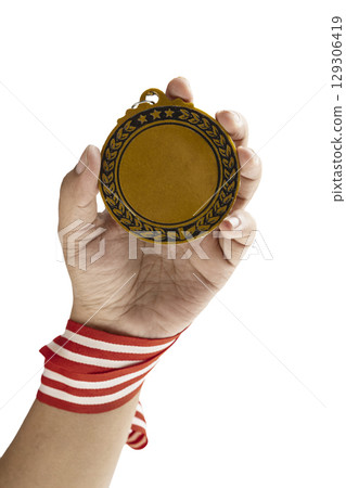 Human hand holding golden award medal suspended from a red and white striped ribbon isolated over a white background. Copy space. Symbol of achievement, recognition, or competition Human hand holding golden award medal suspended from a red and white striped ribbon isolated over a white background. Copy space. Symbol of achievement, recognition, or competition 129306419