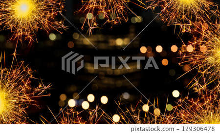 Sparkling border of glowing sparklers against a bokeh blurred backdrop of lights at night. Copy space 129306478