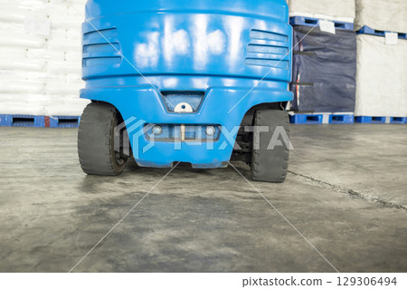 Closeup view of a forklift on a concrete floor inside the warehouse building. Storage, inventory, industry, and logistics 129306494