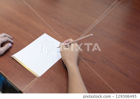 Businessperson writing a note in a notebook on a wooden table. Mockup or copy space 129306495