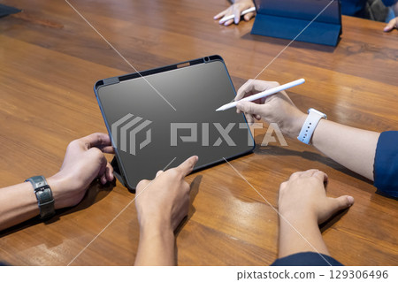Group of business people meeting using a digital tablet device on a wooden table. Mockup or copy space. Concept of teamwork 129306496