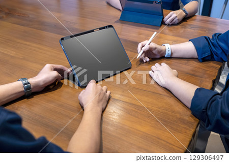 Group of business people meeting using a digital tablet device on a wooden table. Mockup or copy space. Concept of teamwork 129306497