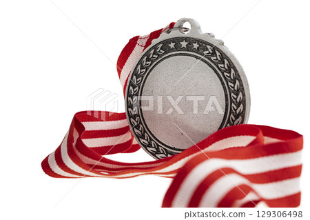 Closeup view of the silver award medal suspended from a red and white striped ribbon isolated over a white background. Copy space. Symbol of achievement, recognition, or competition Closeup view of the silver award medal suspended from a red and white striped ribbon isolated over a white background. Copy space. Symbol of achievement, recognition, or competition 129306498