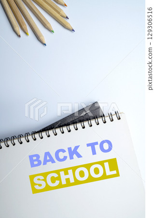 Notebook and a wooden pencil with a message of Back to School isolated over a white background. Concept of Back to School 129306516