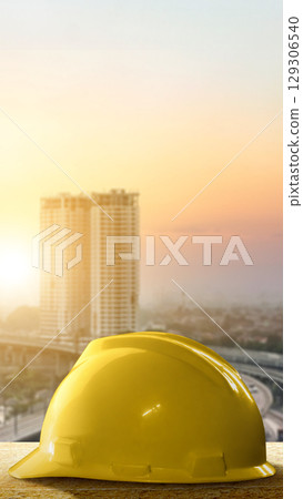 Yellow hard hat safety equipment with a cityscape background. Concept of World Engineer Day Yellow hard hat safety equipment with a cityscape background. Concept of World Engineer Day 129306540
