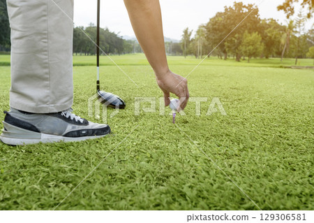 Golfer with a golf club is ready to hit a golf ball on the green grass of a golf course. Concept of sport Golfer with a golf club is ready to hit a golf ball on the green grass of a golf course. Concept of sport 129306581