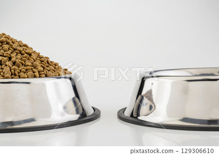 Dog and cat dry food on a stainless steel bowl on a white background Dog and cat dry food on a stainless steel bowl on a white background 129306610