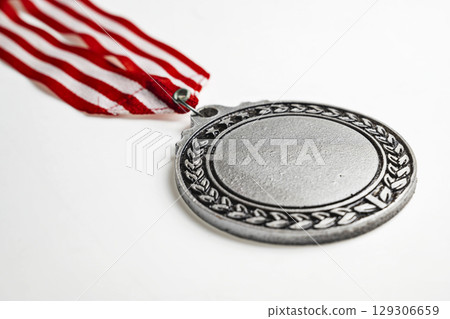 Closeup view of the silver award medal suspended from a red and white striped ribbon isolated over a white background. Copy space. Symbol of achievement, recognition, or competition Closeup view of the silver award medal suspended from a red and white striped ribbon isolated over a white background. Copy space. Symbol of achievement, recognition, or competition 129306659