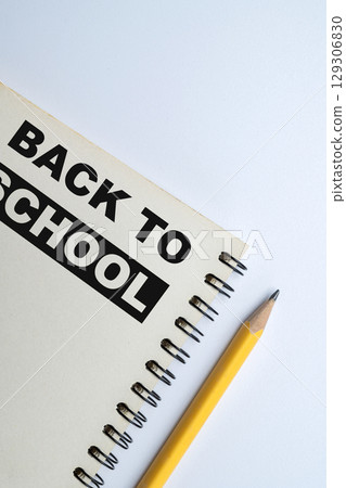 Notebook and a wooden pencil with a message of Back to School isolated over a white background. Concept of Back to School 129306830