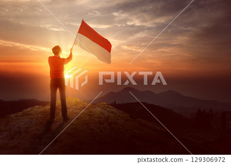 Indonesian southeast asian businessman holding a waving Indonesian national flag to celebrate Indonesia Independence Day on the 17th of August. Concept of Kemerdekaan Indonesia Indonesian southeast asian businessman holding a waving Indonesian national flag to celebrate Indonesia Independence Day on the 17th of August. Concept of Kemerdekaan Indonesia 129306972