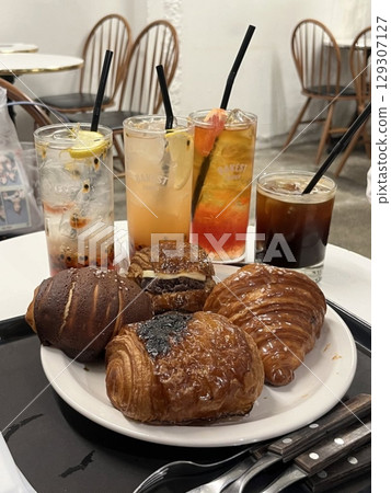 A delightful assortment of desserts displayed in a cozy cafe setting, featuring cakes, pastries, and sweet treats on elegant plates, creating a warm and inviting atmosphere. A delightful assortment of desserts displayed in a cozy cafe setting, featuring cakes, pastries, and sweet treats on elegant plates, creating a warm and inviting atmosphere. 129307127