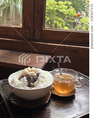 Refreshing patbingsu with fluffy shaved ice, sweet red bean paste, chewy rice cakes, and fresh fruit toppings. A classic Korean dessert, perfect for cooling down on hot days with a delightful taste! 129307135