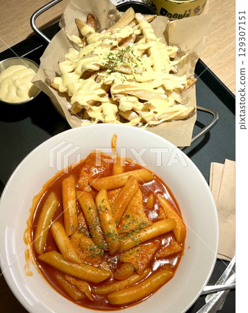 Spicy and chewy tteokbokki paired with crispy potato wedges, creating a perfect balance of heat and crunch for a satisfying Korean street food experience. Spicy and chewy tteokbokki paired with crispy potato wedges, creating a perfect balance of heat and crunch for a satisfying Korean street food experience. 129307151