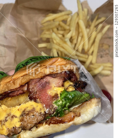 A classic combination of a juicy burger with fresh toppings served alongside golden, crispy French fries. Perfect for a satisfying meal that blends savory flavors and crunchy textures. 129307265