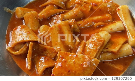 Spicy Korean tteokbokki with chewy rice cakes in a vibrant red sauce, topped with sesame seeds and green onions. A popular street food known for its addictive flavor and satisfying texture. Spicy Korean tteokbokki with chewy rice cakes in a vibrant red sauce, topped with sesame seeds and green onions. A popular street food known for its addictive flavor and satisfying texture. 129307290