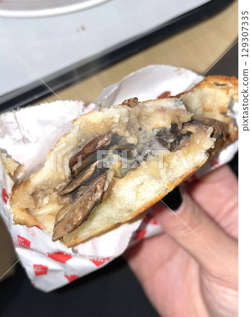 A mouthwatering burger with a juicy patty, fresh lettuce, tomato, and melted cheese, all nestled in a soft bun. Perfect for food photography, showcasing the indulgence of classic comfort food. 129307335