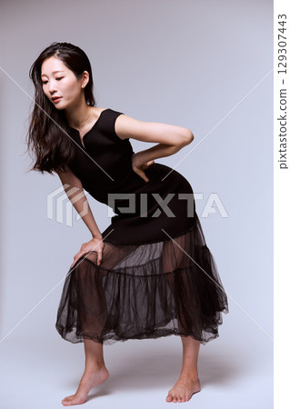 一位身穿黑色連身裙的女模特兒的工作室肖像 129307443