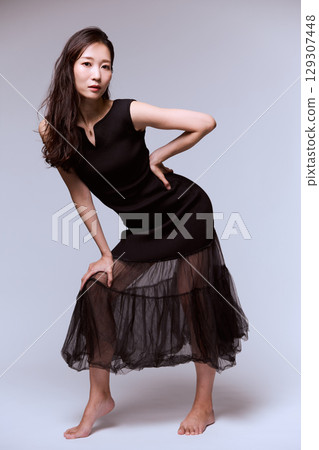 Studio portrait of a female model posing in a black dress 129307448