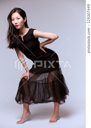 Studio portrait of a female model posing in a black dress 129307449
