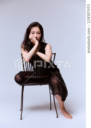 一位身穿黑色連身裙的女模特兒的工作室肖像 129307453