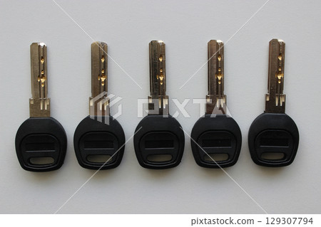 Same Steel Lock Keys With Plastic Heads Laid Out In A Row On White Surface   129307794