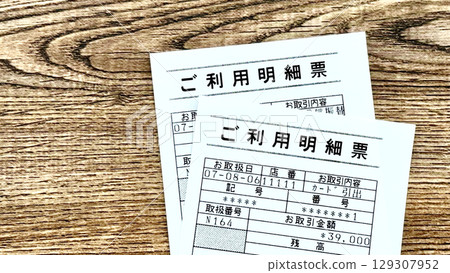 Two bank ATM receipts, brown board background, overhead view 129307952