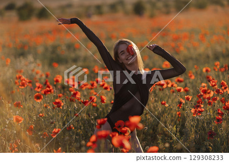 Poppy Field Woman Enjoy: Golden hour joyful female poses with red poppy flower, spring sunset nature. Poppy Field Woman Enjoy: Golden hour joyful female poses with red poppy flower, spring sunset nature. 129308233