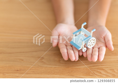 Elementary school boy's hand holding a model of a wheelchair 129308855