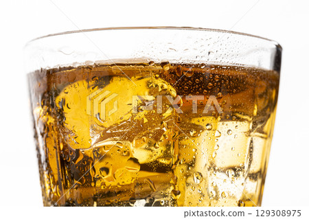 The moment ice is poured into a glass of barley tea on a white background The moment ice is poured into a glass of barley tea on a white background 129308975