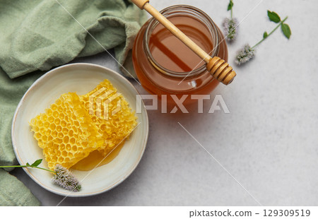 Honeycomb and honey jar with wooden dipper on marble table 129309519