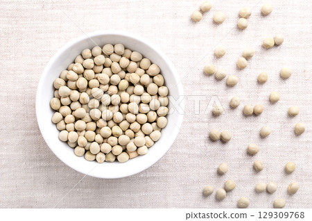 Dried green peas in white bowl on linen. Seeds of Pisum sativum, a pulse, vegetable and fodder crop, that can be reconstituted in hot water. Good source of protein, fiber, magnesium, and potassium. Dried green peas in white bowl on linen. Seeds of Pisum sativum, a pulse, vegetable and fodder crop, that can be reconstituted in hot water. Good source of protein, fiber, magnesium, and potassium. 129309768
