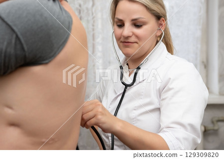 Medical professional listens with a stethoscope. Compassionate care in a clinic. Trust the skilled hands for accurate health checks. Medical professional listens with a stethoscope. Compassionate care in a clinic. Trust the skilled hands for accurate health checks. 129309820