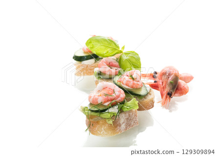 Appetizing appetizers with shrimps, sauce and cucumbers on a white background Appetizing appetizers with shrimps, sauce and cucumbers on a white background 129309894