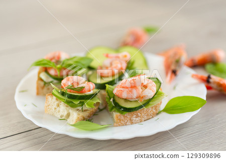 Light festive canapes with seafood, greens and fresh vegetables 129309896