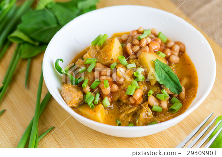 Vegetable stew with meat and potatoes in a white bowl on the table 129309901