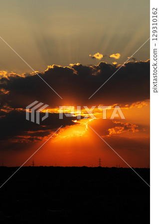 Dramatic sunset with sun rays bursting through thick clouds 129310162
