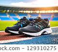 Running shoe pair on track field with stadium background in warm sunlight, ready for energetic outdoor exercise 129310275