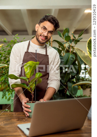 Flower shop assistant presenting plants to the audience in internet 129310419