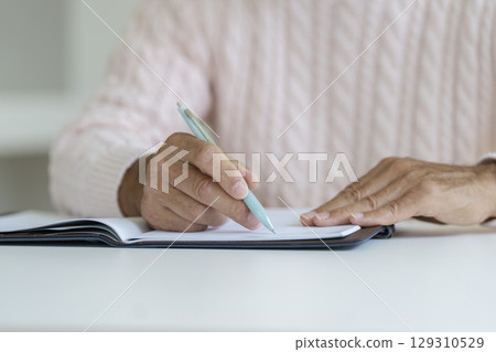Senior man's hand holding a pen 129310529