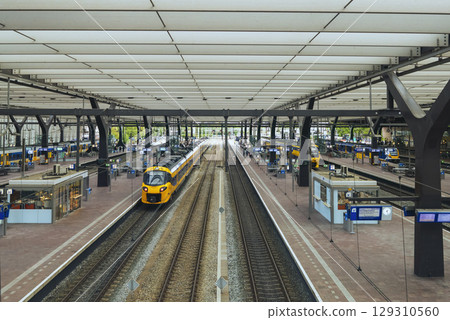 ROTTERDAM, NETHERLANDS, August 1, 2025. Yellow and blue NS train on the platform of Rotterdam Central Station with passengers ROTTERDAM, NETHERLANDS, August 1, 2025. Yellow and blue NS train on the platform of Rotterdam Central Station with passengers 129310560
